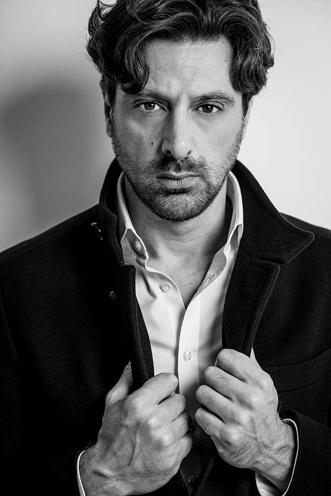 black-and-white-portrait-photos-of-man-gazing-into-camera-holding-black-coat-collar