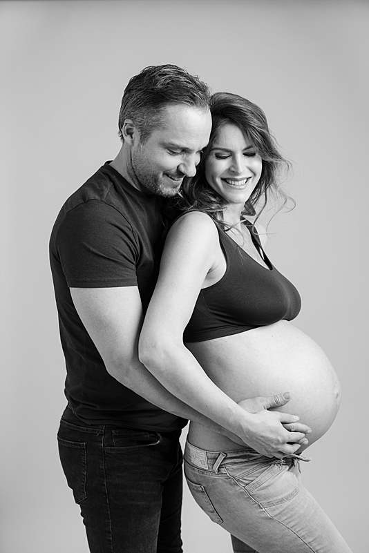 Husband-cuddling-wife-maternity-photo-shoot-pregnant-woman-in-crop-top-jeans-london-photographer