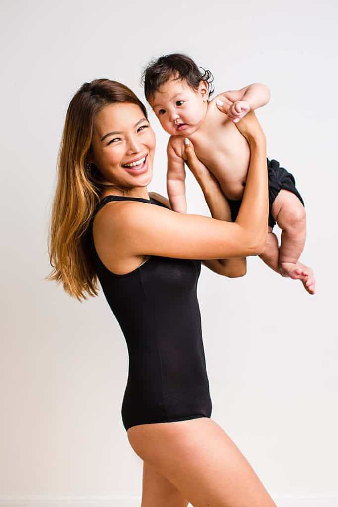 Fashion-inspired mother daughter photoshoot in London, with mother in black bodysuit lifting her baby daughter, styled in a modern editorial look.