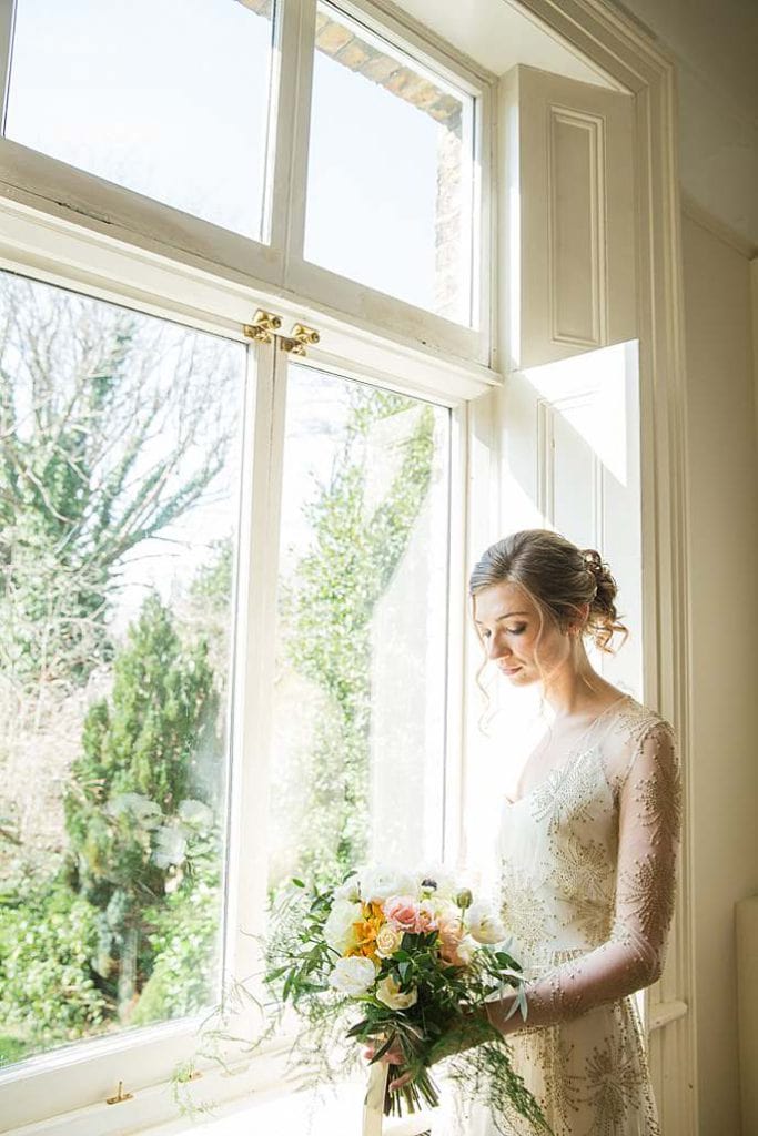 bride-in-anticipation-by-window-facing-garden-london-fine-art-photographer