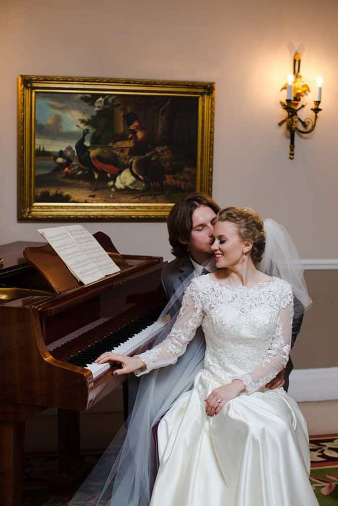 groom-kissing-bride-in-front-of-pinao-bride-smiling-hendon-london