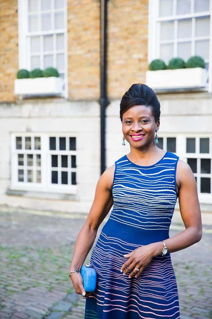 Personal-brand-photography-nigerian-woman-stylist-strolling-down-the-street-in-striped-blue-dress-carrying-handbag-looking-happy