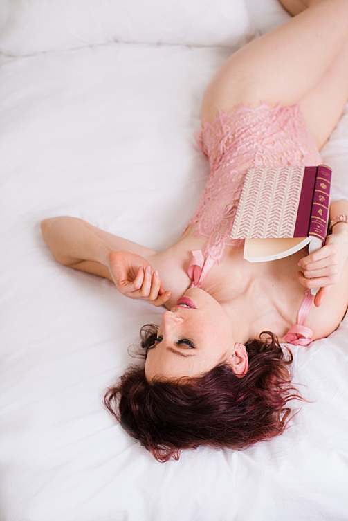 london-boudoir-photographer-woman-in-pink-lace-bodysuit-lying-in-bed-with-book