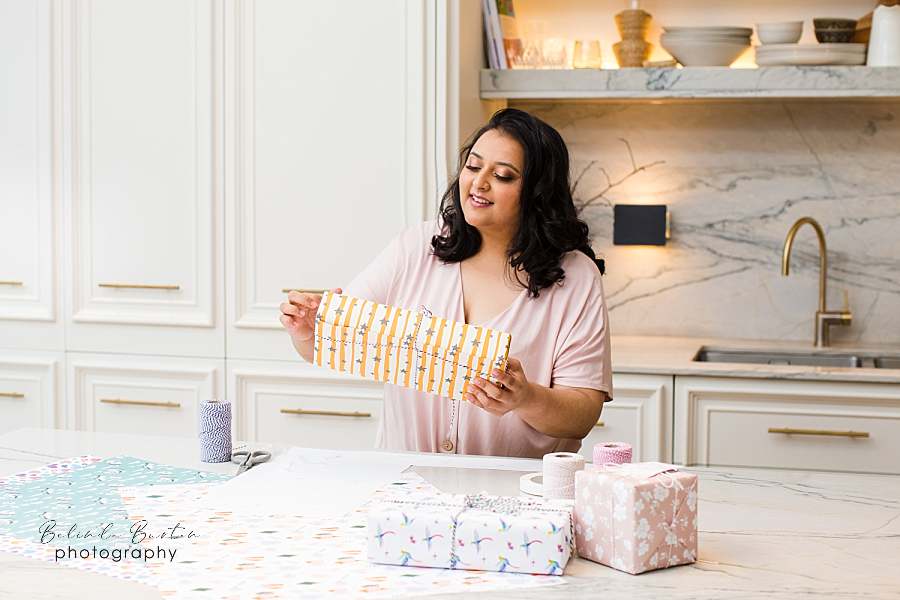 personal-brand-image-female-entrepreneur-pastel-casual-style-outfit-to-wear-to-photoshoot-by-london-portrait-photographer-wrapping-presents-on-white-marble-kitchen-work-top