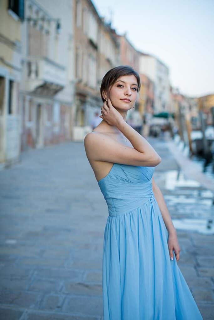girl-in-blue-dress-in-front-of-cobbled-street-venetian-terraced-house-by-canal-posing-for-venice-photo-shoot.