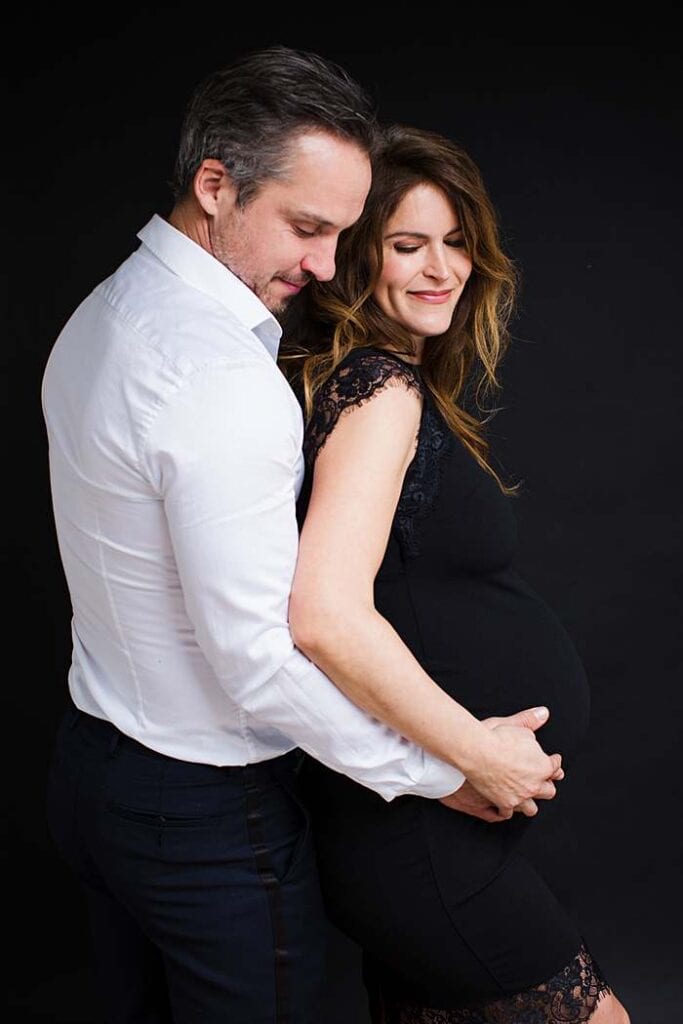 couple-pregnancy-photo-man-in-black-shirt-embracing-woman-in-black-dress-by-maternity-photographer-london