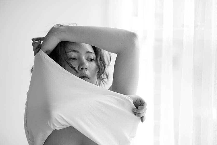 boudoir-photos-of-girl-taking-off-white-t-shirt-in-front-of-window