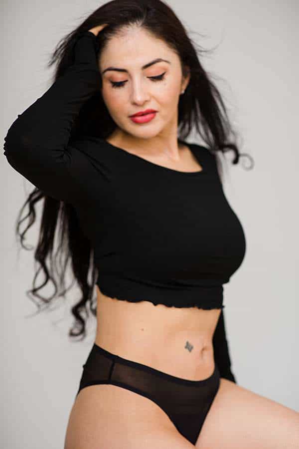 boudoir-photos-of-woman-in-black-cropped-top-black-pants-looking-away-hair-flying-by-london-boudoir-photographer