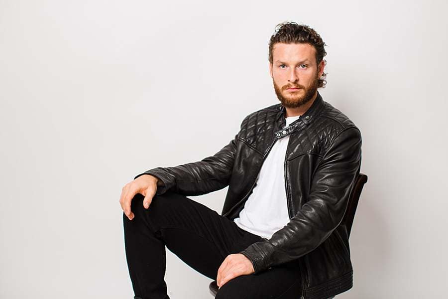 male-portrait-photography-man-with-curly-hair-and-beard-in-white-tee-black-leather-jacket-black-jeans