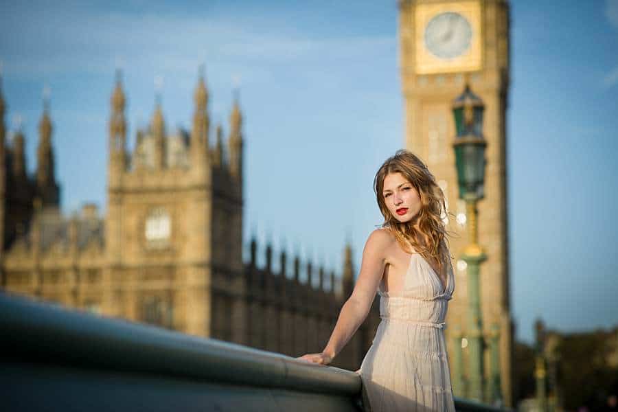 Woman in a white dress posing on Westminster Bridge with Big Ben in the background with this tourist site being among popular London photo spots