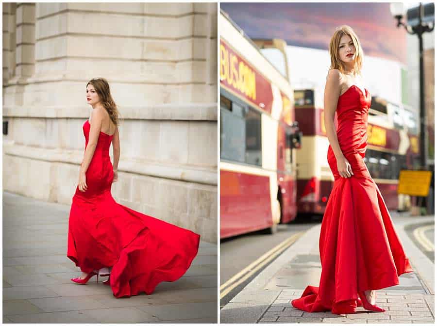 Woman in a flowing red dress posing near a stone wall and in front of red London buses