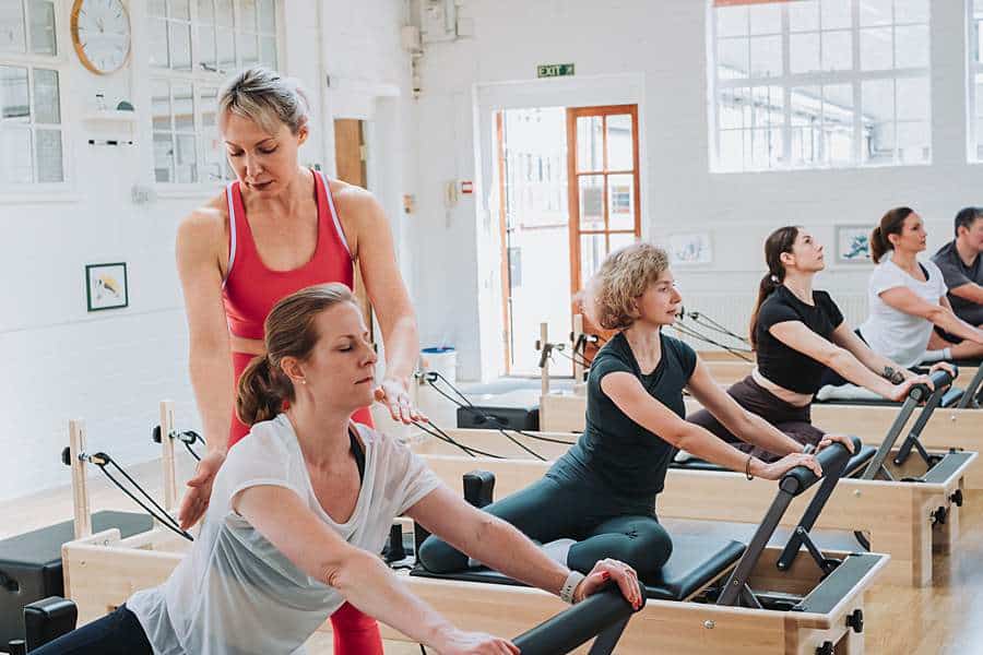 Pilates instructor providing personalised coaching during a reformer class, photographed for a lifestyle branding photoshoot in London.